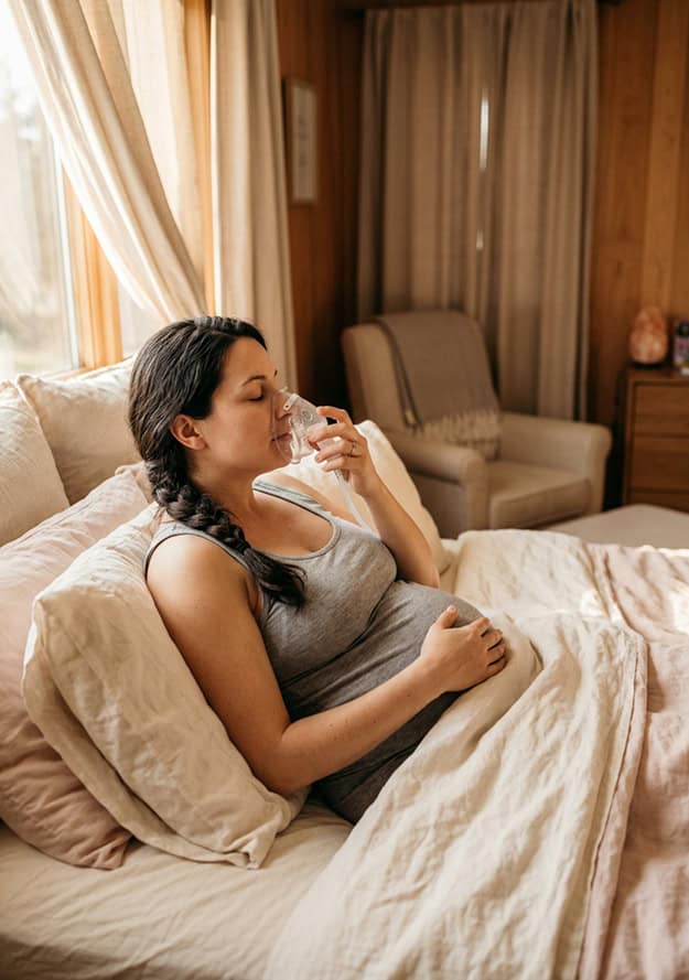 Pregnant woman using a nitrous oxide mask for natural labor pain relief at a San Diego birth center